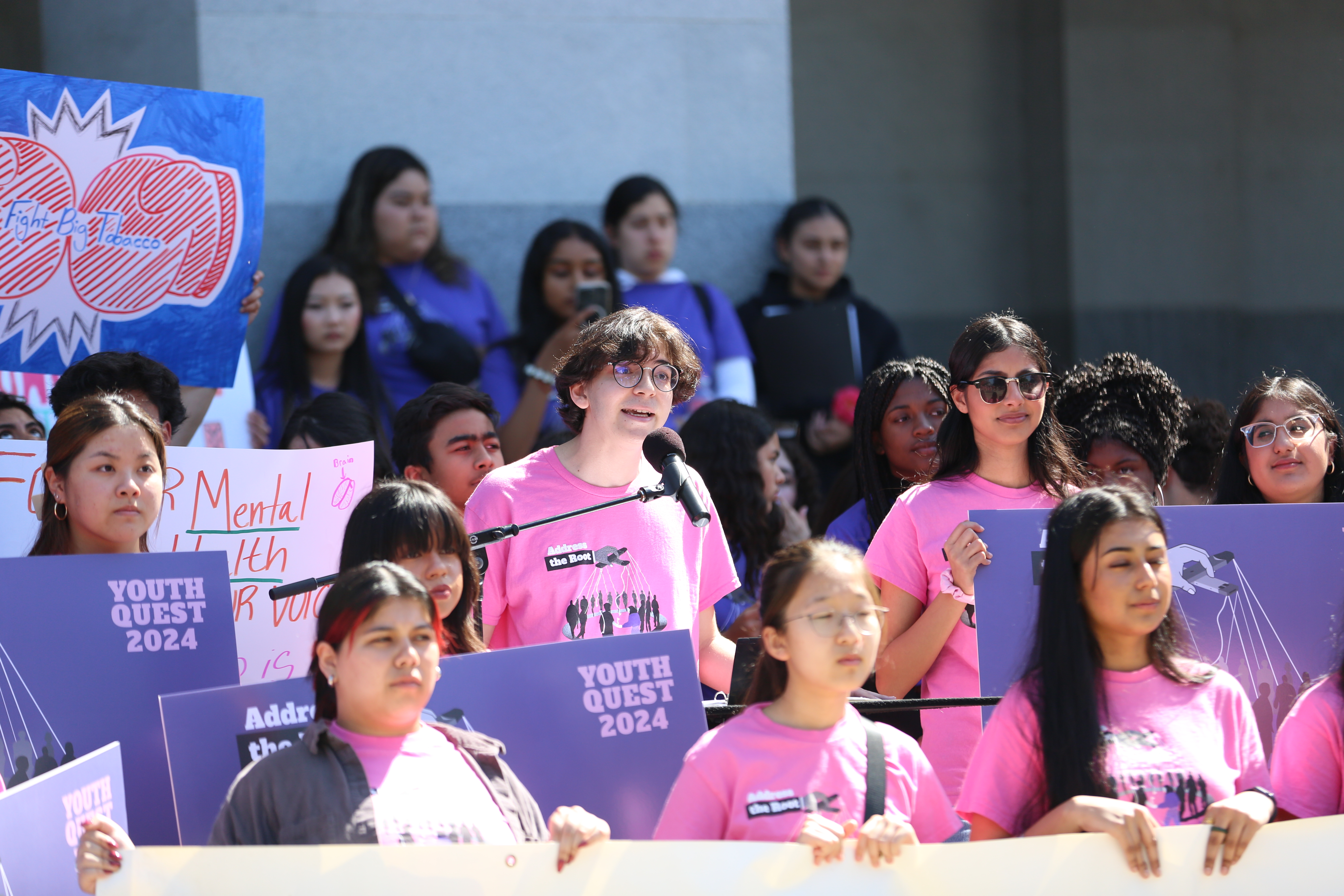 A student speaks into a microphone surrounded by peers who are protesting tobacco industry manipulation of young people.