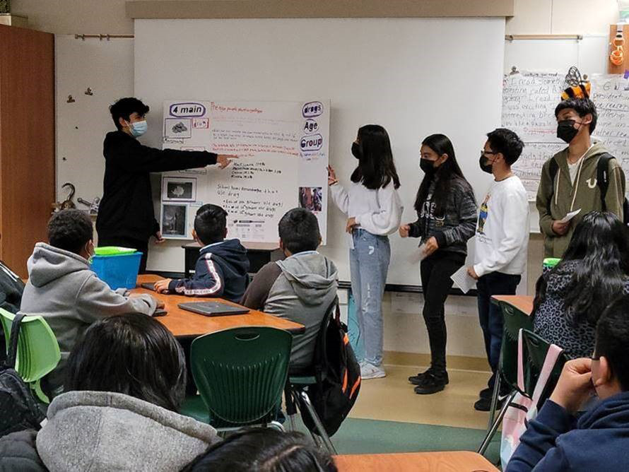 Five young students in front of a classroom present about tobacco to their peers.