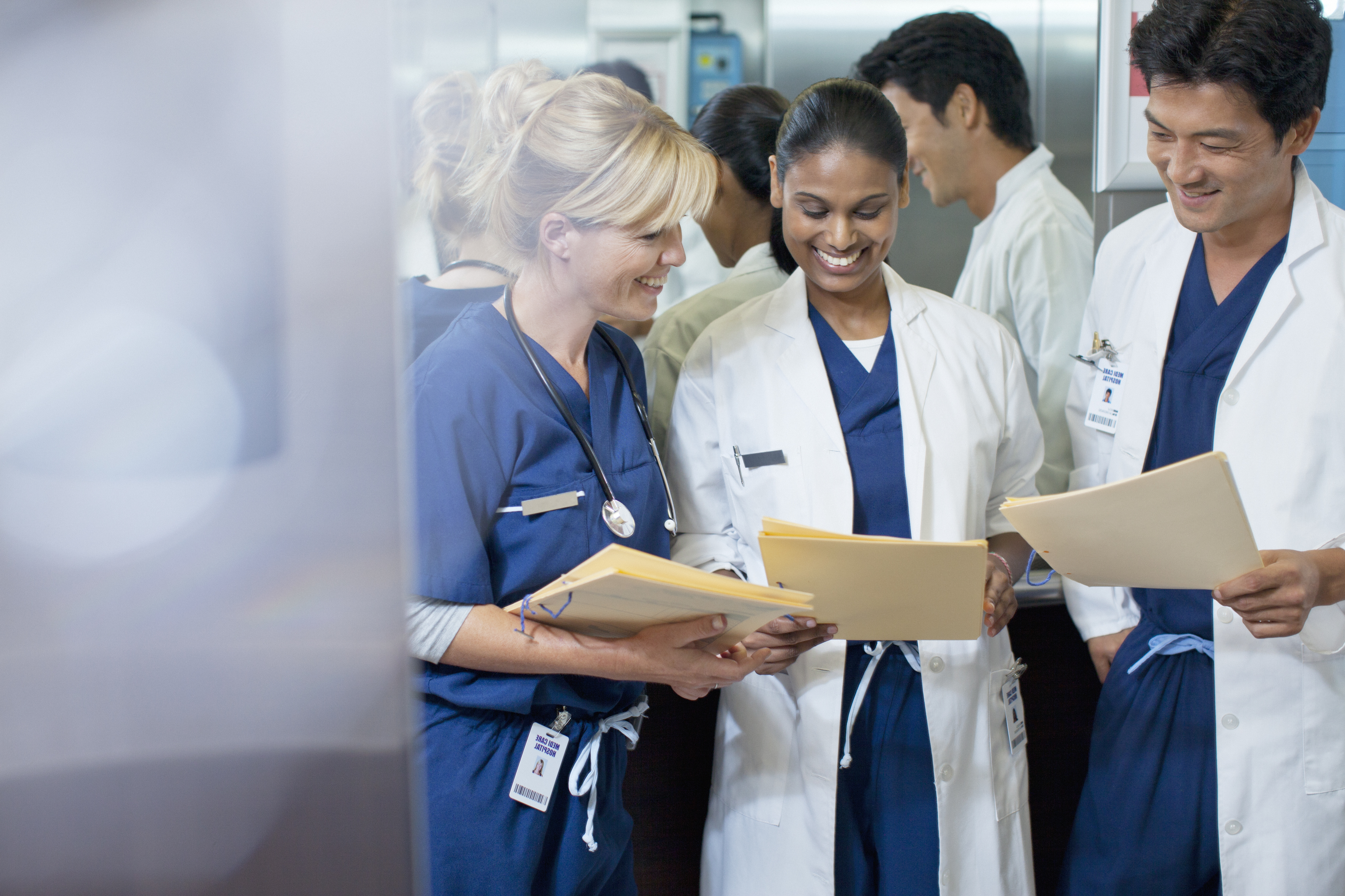 Medical professionals with file folders in hand gathering for discussion
