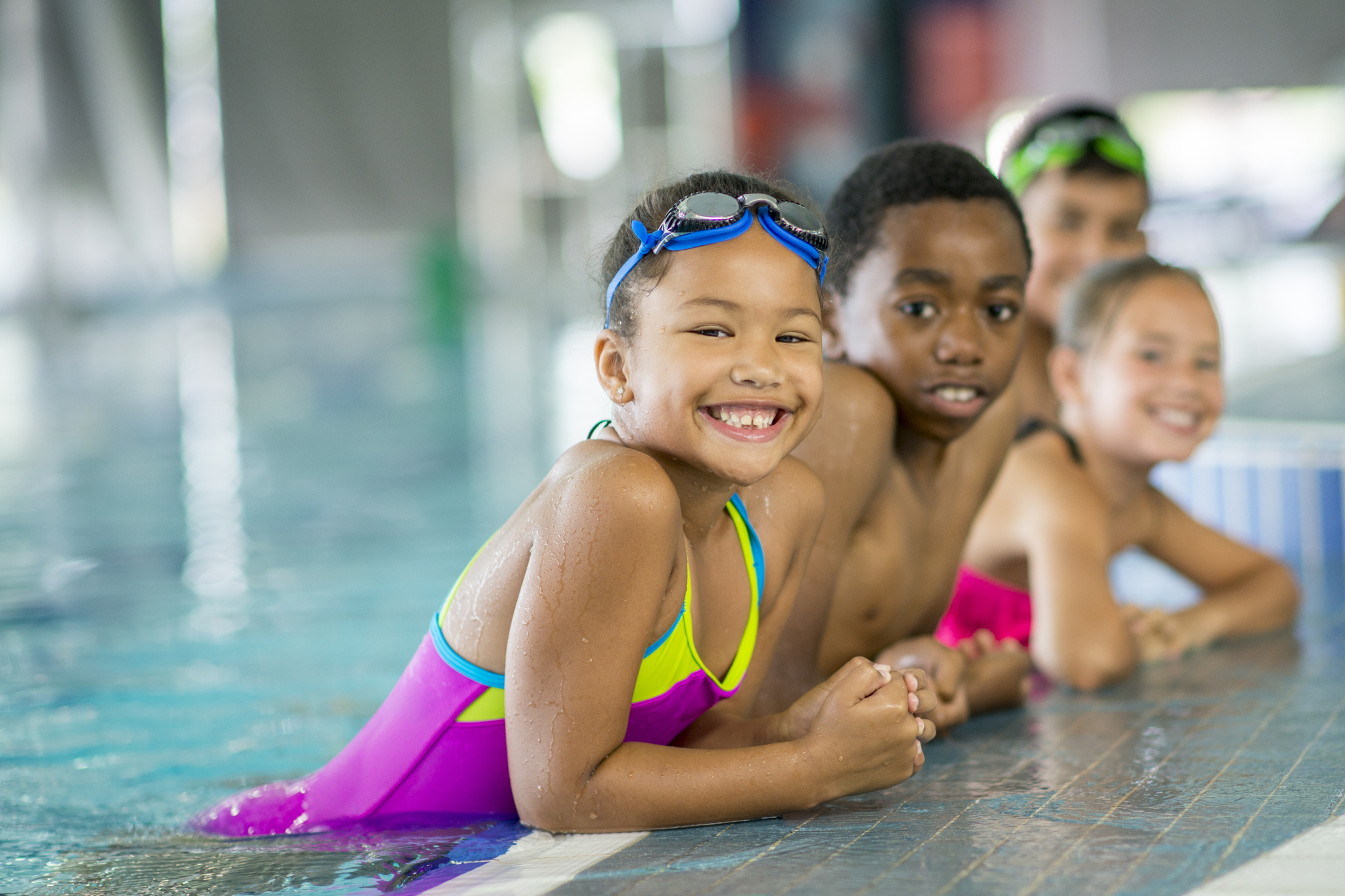 Kids leaning on edge of swimming pool