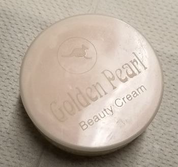 A peach-ish beige round container with the words "Golden Pearl Beauty cream" inscribed on the cap