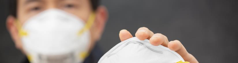 person wearing and holding N95 mask