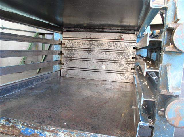 Inside view of gated lower part of machine with metal floor and ceiling and metal horizontal slats on the sides.