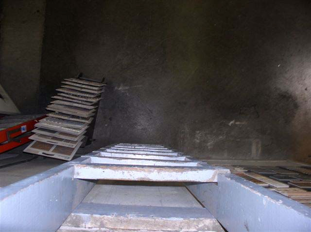 A narrow wooden ladder at a vertical angle as seen from the top with a concrete floor beneath it.