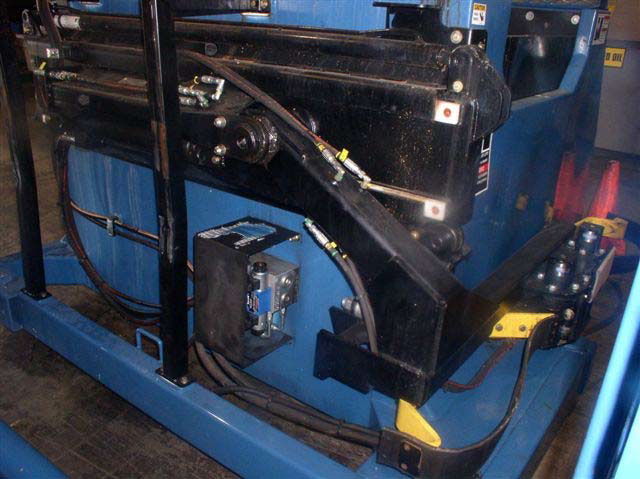 Hydraulic wires and large, connected metal brackets with joints and motors are attached to the back of the blue collection bin.