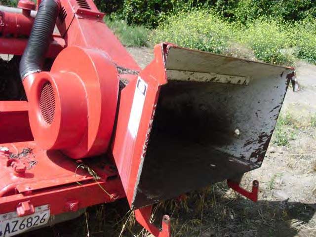 A view of the back of the chipper where branches are loaded. There are two rusted metal hooks protruding from the bottom.