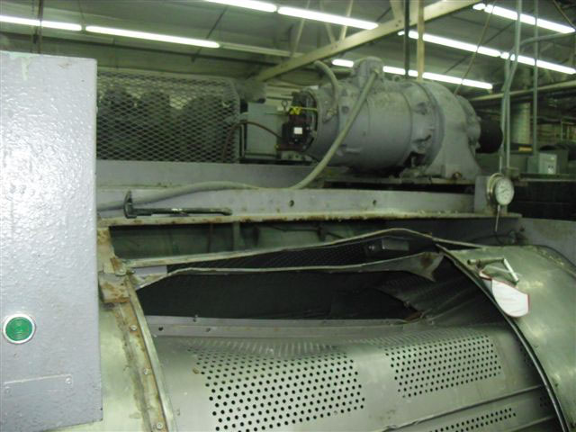 Close-up of opening of machine with a large dent and bent metal on top where workers tried to pull the trapped worker out of the opening.
