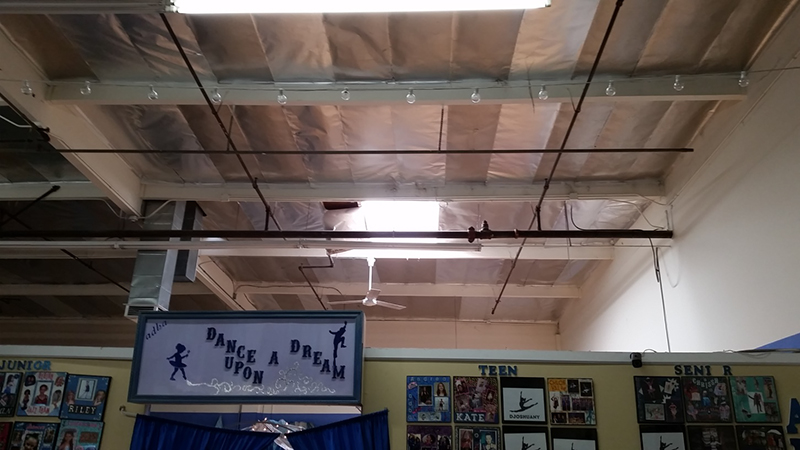 An interior view showing the skylight above a room divider listing dance classes.