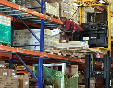  Worker retrieving item off shelf using a  order picker forklift. 