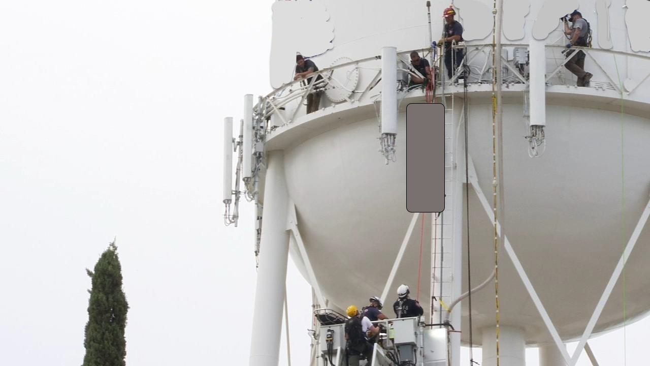 Rescuers on watertower catwalk, lowering victim, whose body is greyed out.