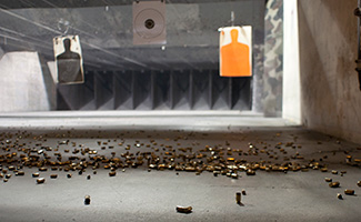 Bullets lie on the floor under hanging targets in a shooting range.