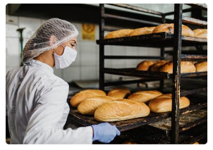 Bakery worker taking bread from oven