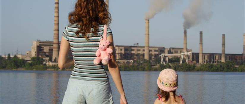 Mother and daughter look at polluting factory