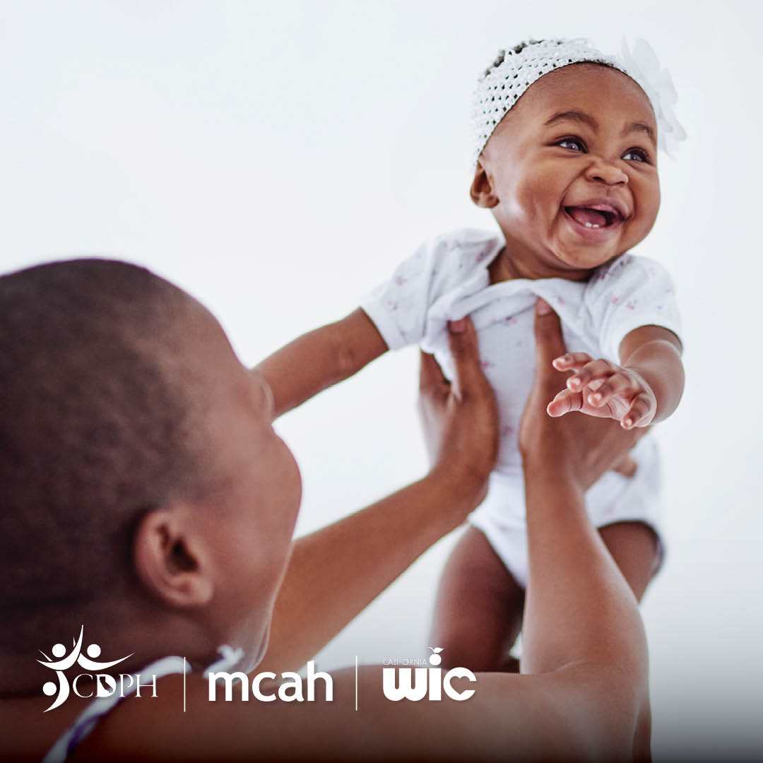 Black women holding up her joyous baby