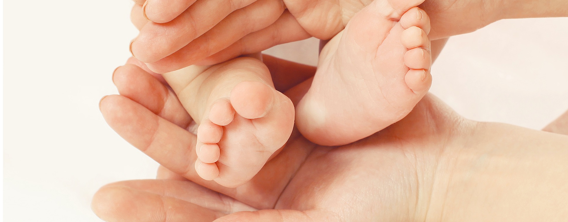 Close up short of adult female hands holding infant feets