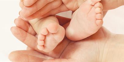 Infant feet rested in parent's hands