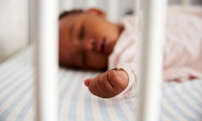 Newborn baby sleeping in a crib on his back