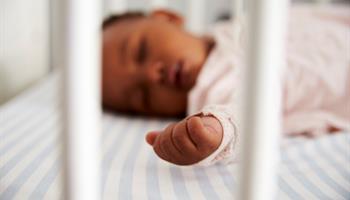 Newborn infant sleeping on his back in crib