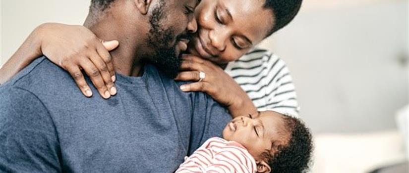 Close-up of black couple looking lovingly at their infant