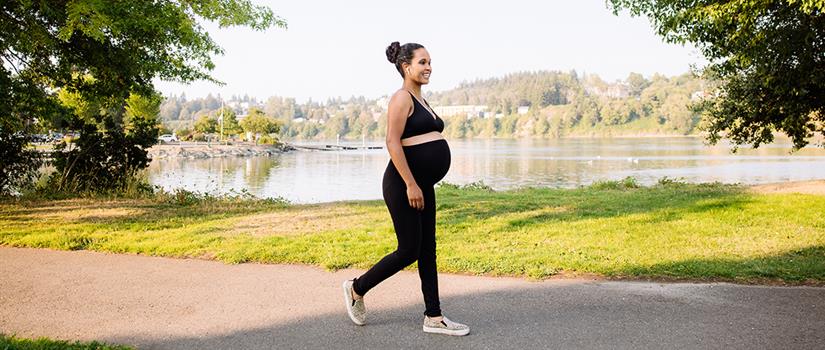 Pregnant individual walking in park, enjoying the natural scenery