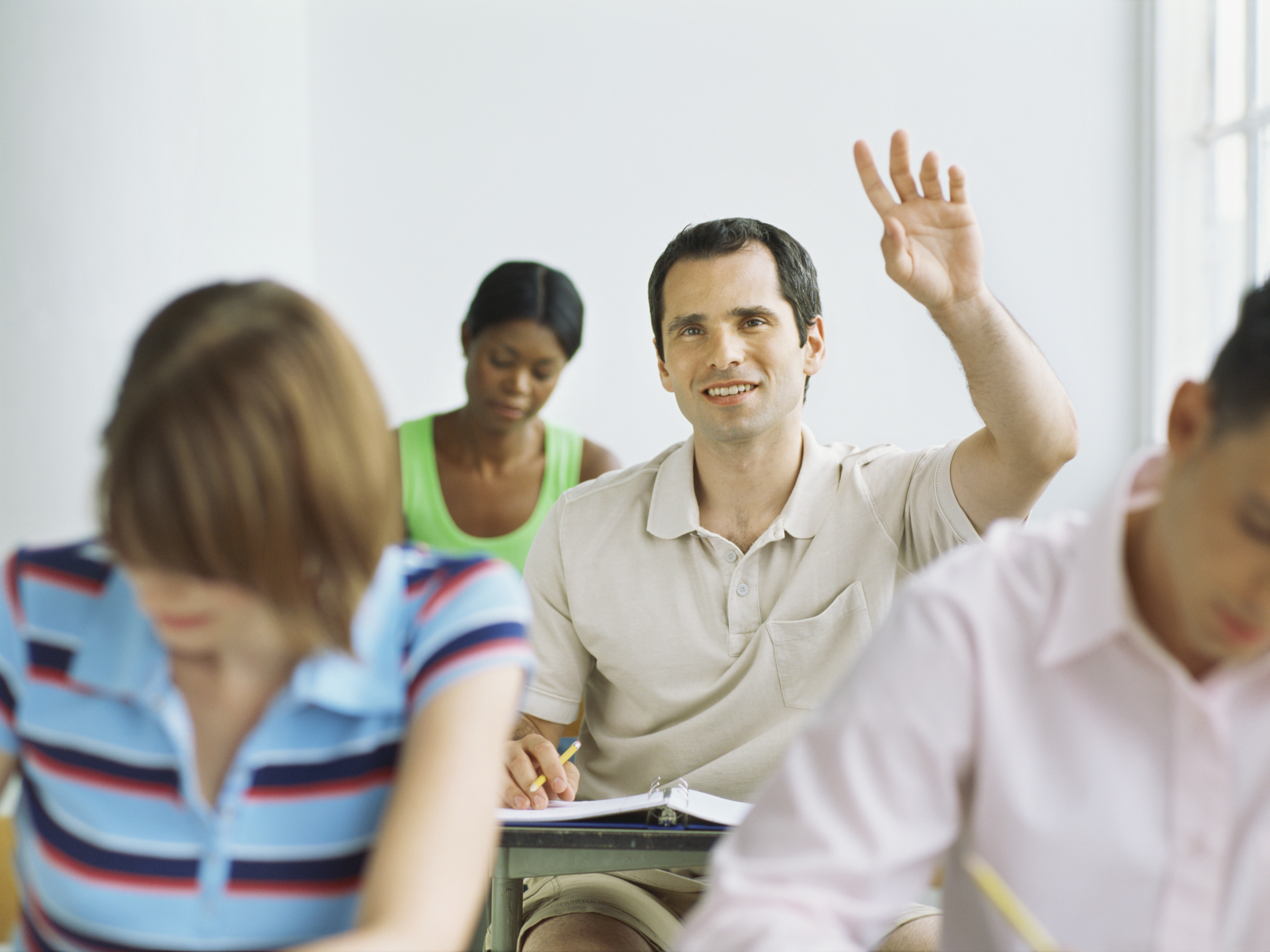 Man in classroom raising his hand