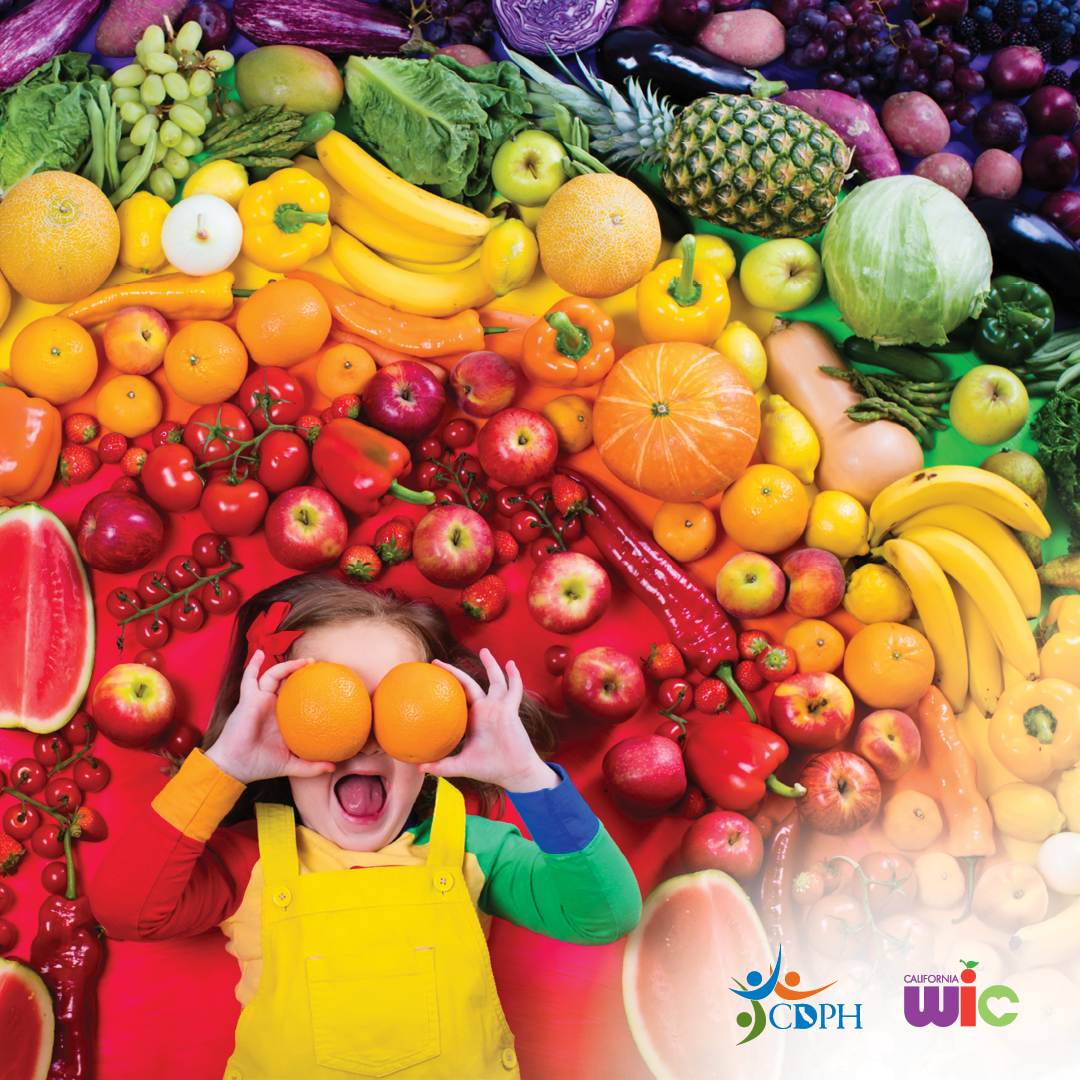 Child holding oranges over eyes.Multi-colored fruits and veggies.