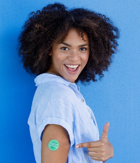 Woman points to her newly vaccinated arm