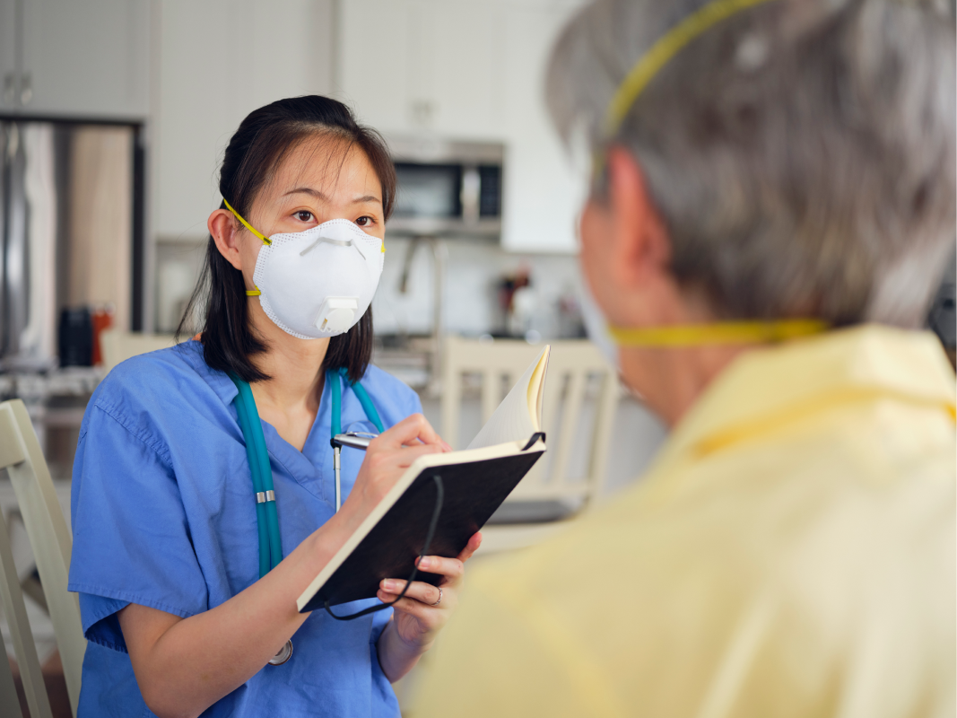A healthcare worker with an N95 respirator takes patient notes. Patient is also wearing N95
