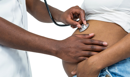 Person holding a stethoscope on a pregnant woman's belly.