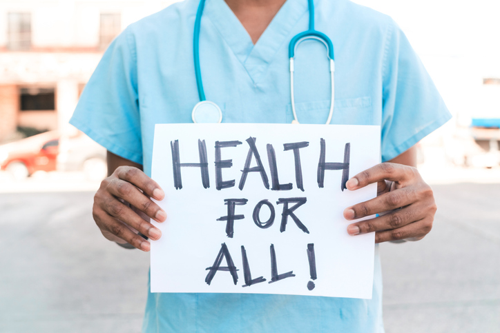 Medical Professional holding "Health for all" sign