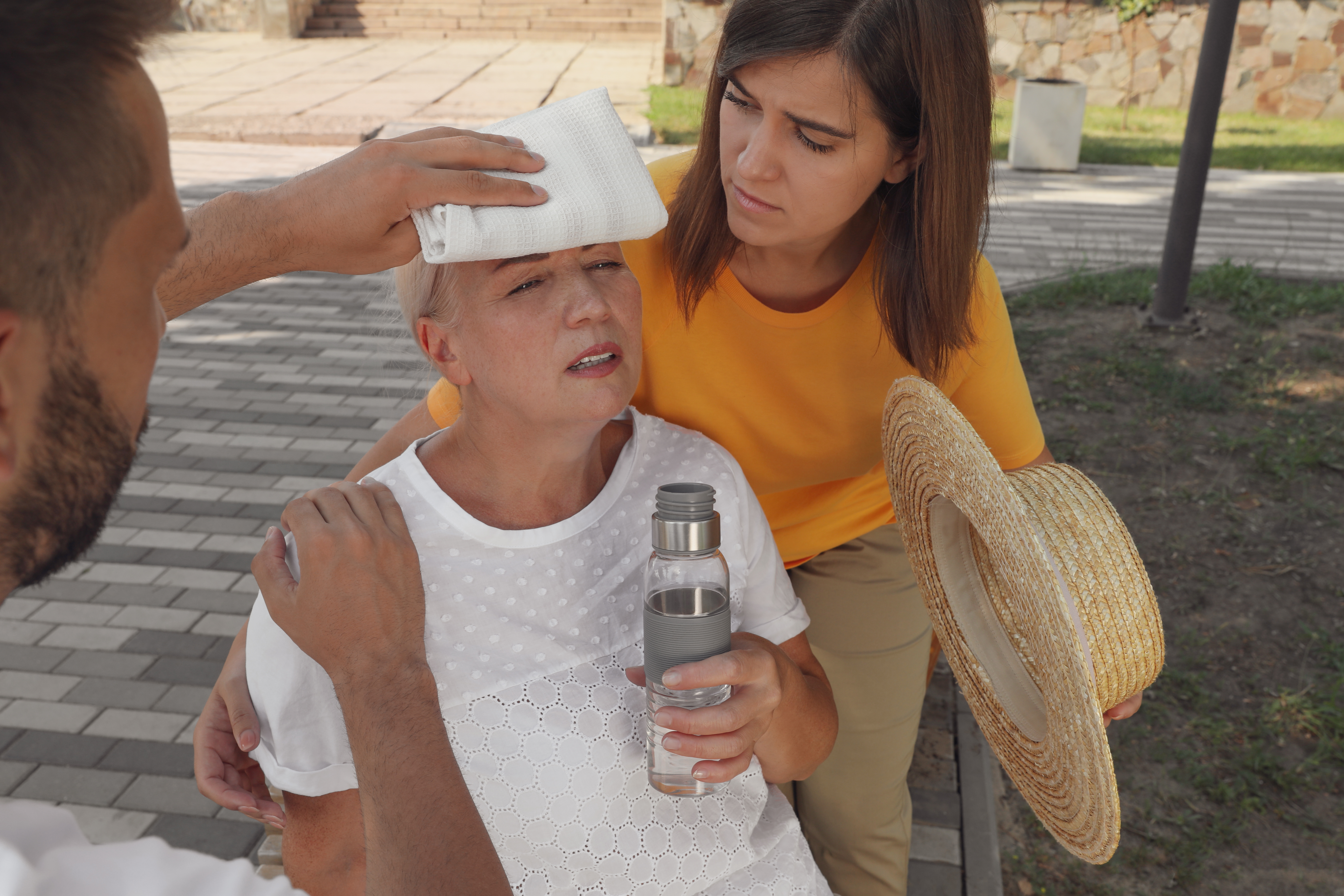 People helping older woman cool off from the heat