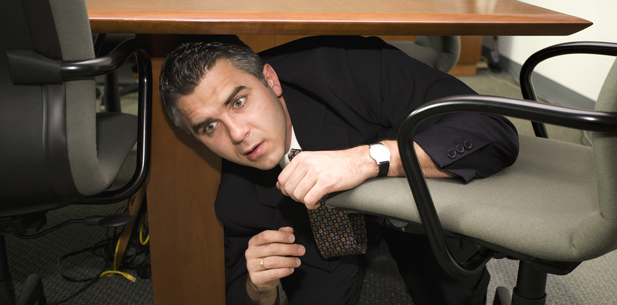 Businessman hiding under a desk