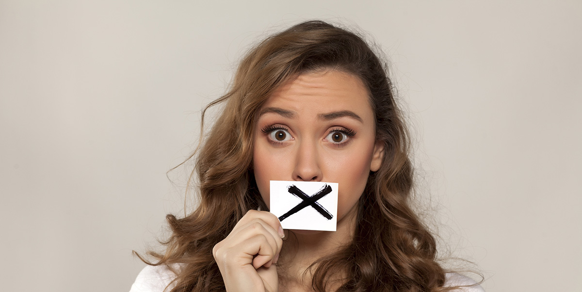 Woman covering her mouth the an X