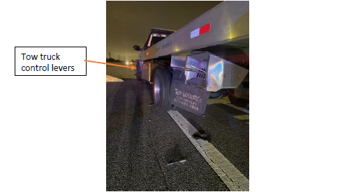 The tow truck partially in the #6 lane with control levers in front of the back tire.