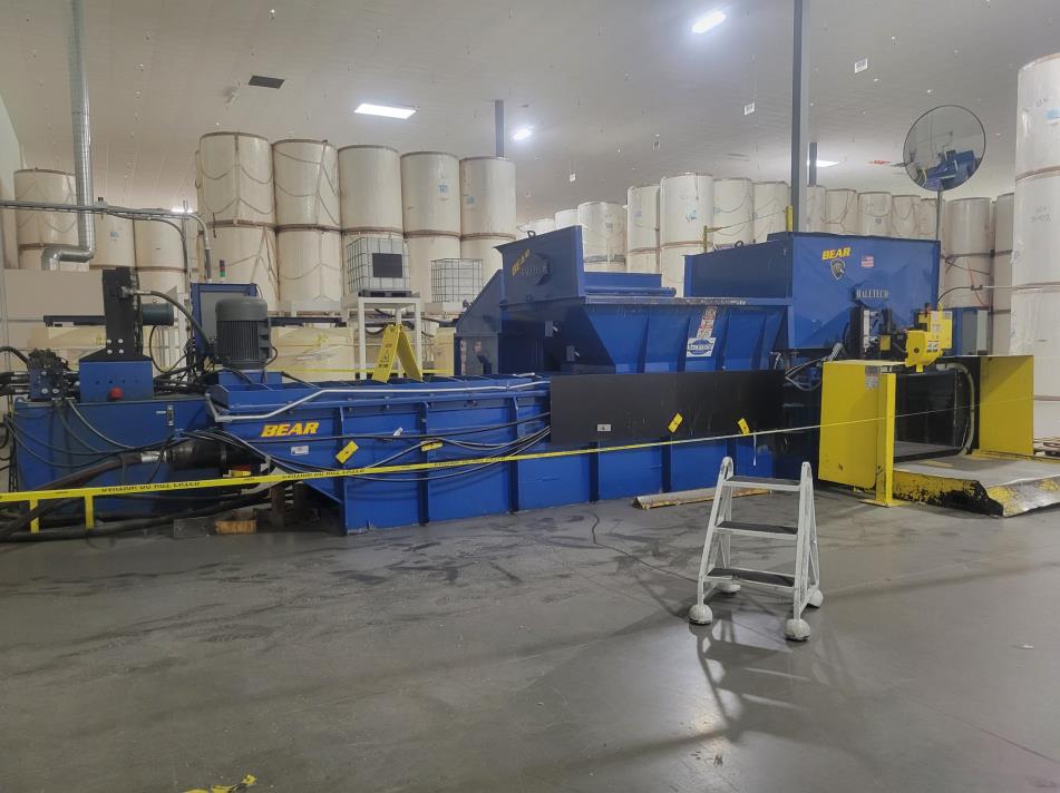 An industrial recycling baler with input hopper, indoor. An industrial recycling baler with input hopper, indoor.