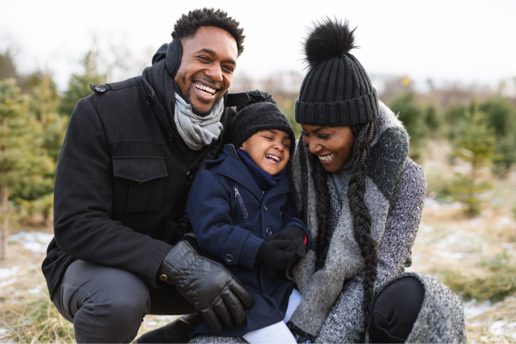 Family of three smiling outside wearing winter clothes