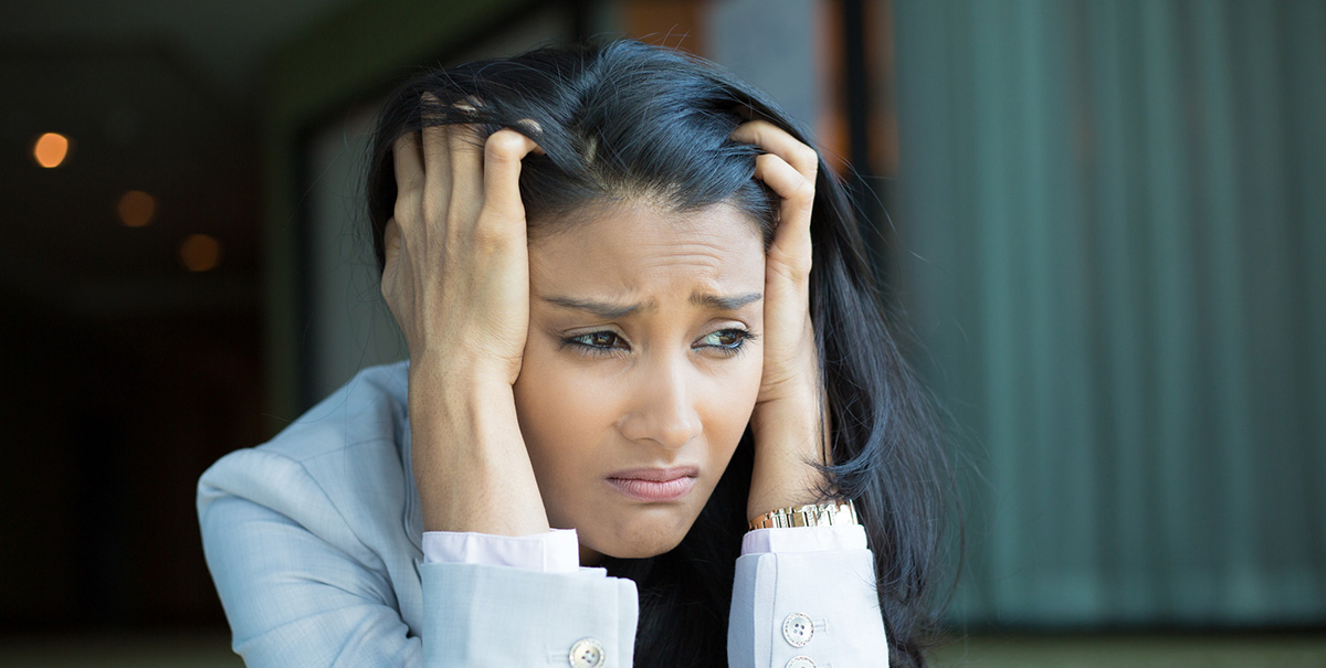 Woman looking stressed while holding her head and hair