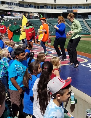 Dr Smith dancing with fruits and veggies at Raley Field